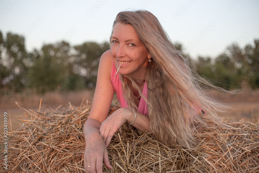 blonde girl lying on a haystack and smiling blonde girl lying on a haystack and smiling