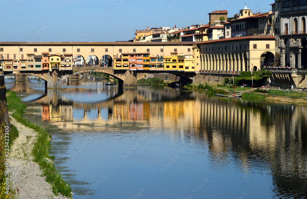 The famous Ponte Vecchio and Uffizi gallery in Florence reflected on the waters of the river Arno. Italy.