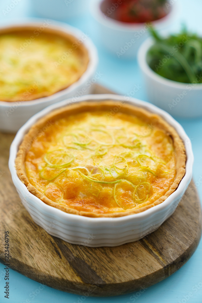 Gluten free leek mini quiches on a wooden board served with fresh rukkola, tomatoes and cheese Gluten free leek mini quiches on a wooden board served with fresh rukkola, tomatoes and cheese