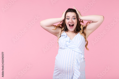 Beautiful pregnant woman in striped dress on pink background