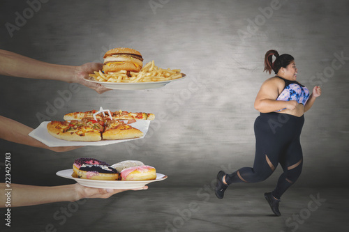 Slika na platnu Fat woman escaping from unhealthy foods