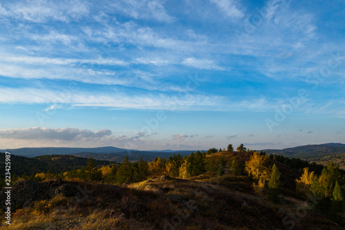 Mountains, autumn forest and blue sky with clouds