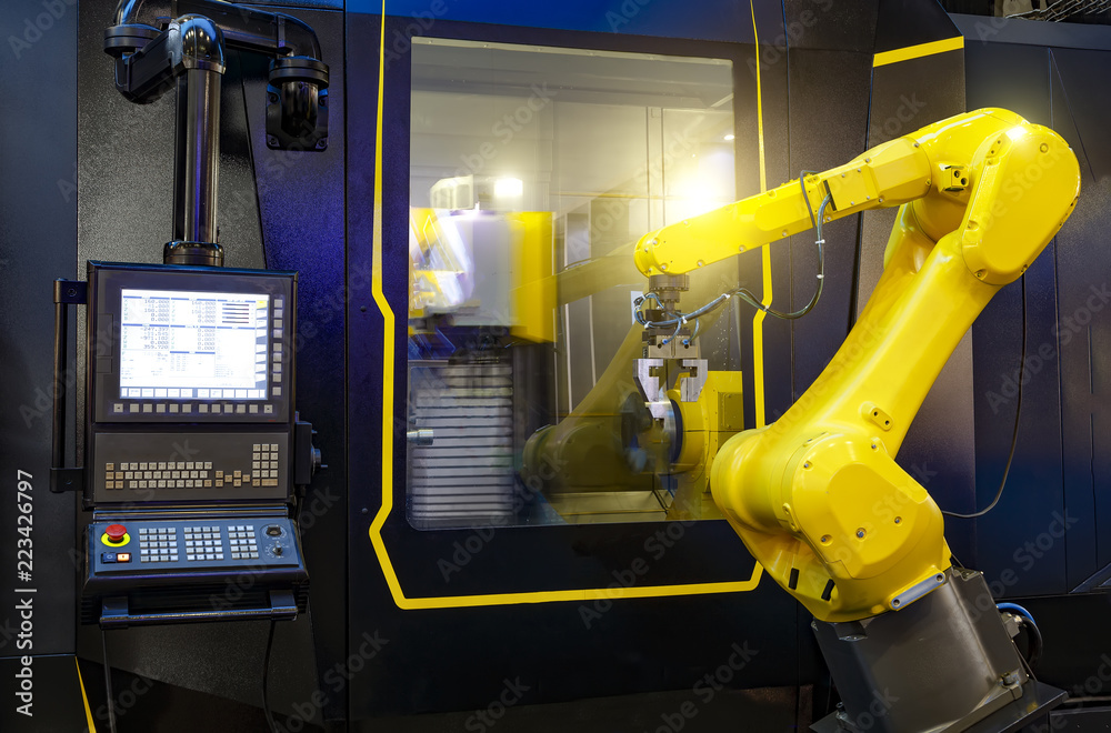 robotic hand machine tool at industrial manufacture factory working in conjunction with a numerically controlled machine robotic hand machine tool at industrial manufacture factory working in conjunction with a numerically controlled machine