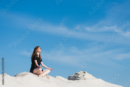 Smiling girl in lotus pose at sand dunes