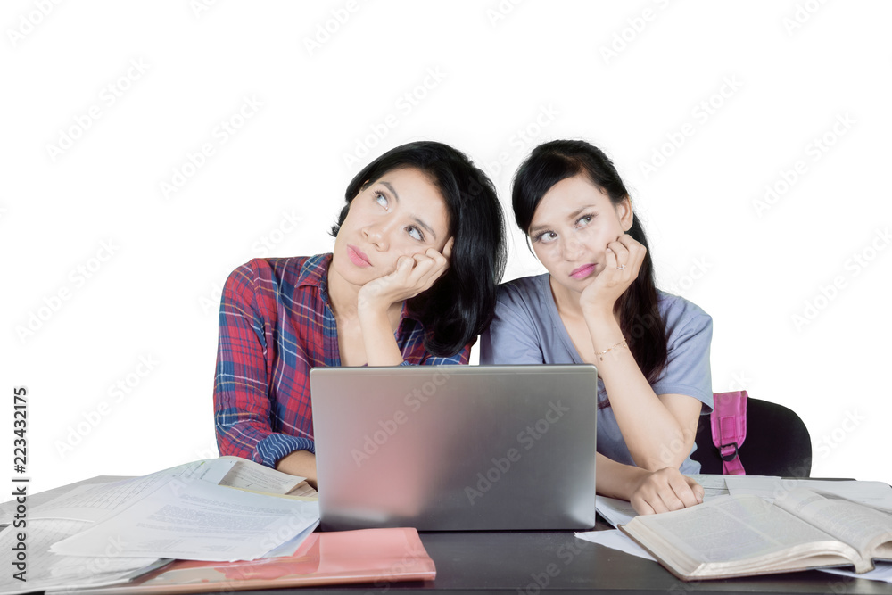 Pensive female students studying on studio Pensive female students studying on studio