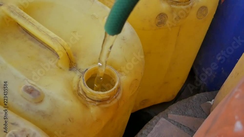 Filling clean water in container with hoze pipe at rural fountain photo