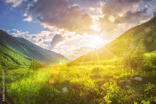 Sunny mountains landscape. Mountain range and yellow sunlight on grassy hills. Amazing sunset in highlands. Svaneti nature scenery. Vivid sun over beautiful wild nature. Vibrant landscape. #223436171