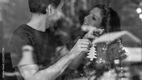 Greyscale image of a loving young couple decorating Christmas tree