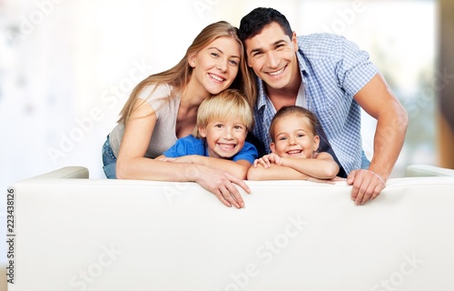 Beautiful smiling family sitting at sofa on background