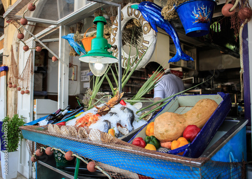 Fresh healthy colorful vegetables fish anf wine on wooden table on the street, Greece.