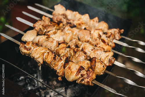 Appetizing shish kebab roasted on skewers on open air charcoal grill. Shish kebab with smoke