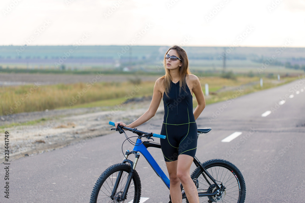 A girl riding a mountain bike on an asphalt road, beautiful portrait of a cyclist at sunset A girl riding a mountain bike on an asphalt road, beautiful portrait of a cyclist at sunset