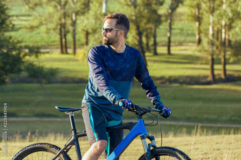 Cyclist in shorts and jersey on a modern carbon hardtail bike with an air suspension fork Cyclist in shorts and jersey on a modern carbon hardtail bike with an air suspension fork
