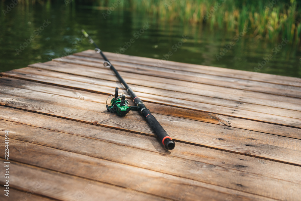 Fishing rod, spinning reel on the background pier river bank