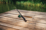 Fishing rod, spinning reel on the background pier river bank.  Misty morning. wild nature. The concept of rural getaway. Article about fishing day.