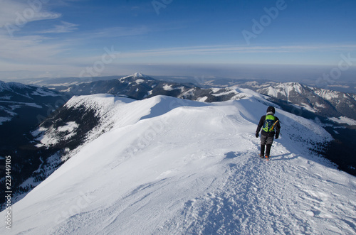 Man hiking in Polish Western Tatra mountains during sunny day in winter.