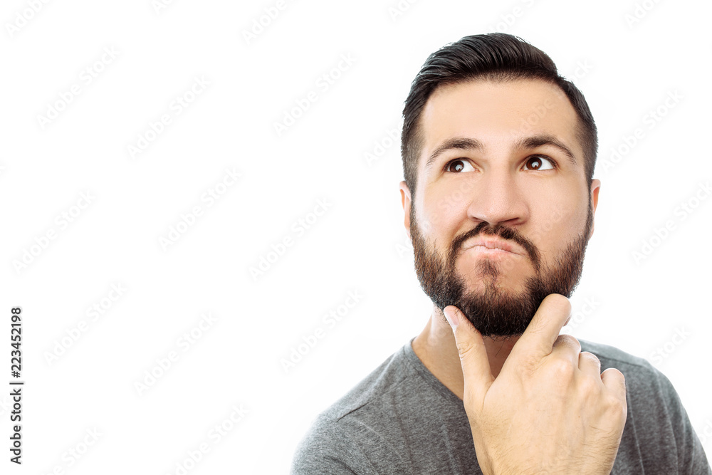 Portrait of brooding bearded man in grey t-shirt looking up and putting hand on face isolated on white background Portrait of brooding bearded man in grey t-shirt looking up and putting hand on face isolated on white background