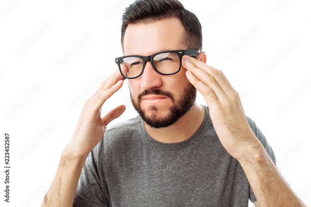 Portrait of brooding bearded man in grey t-shirt looking up and putting hand on face isolated on white background