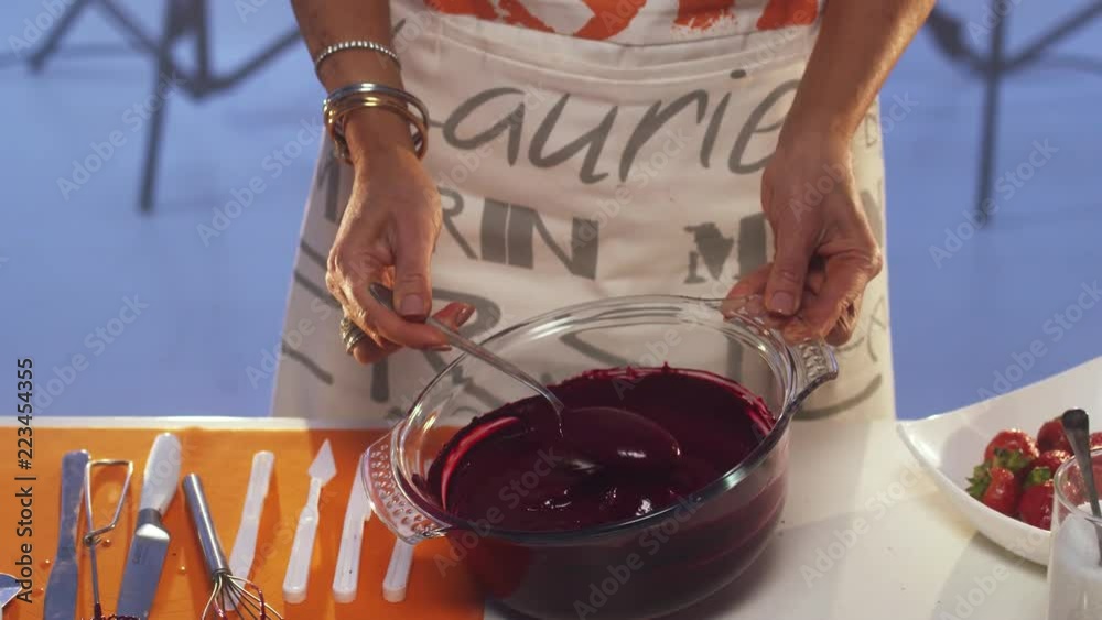 Violet substance in slow motion is dripping from a spoon into big glass ...