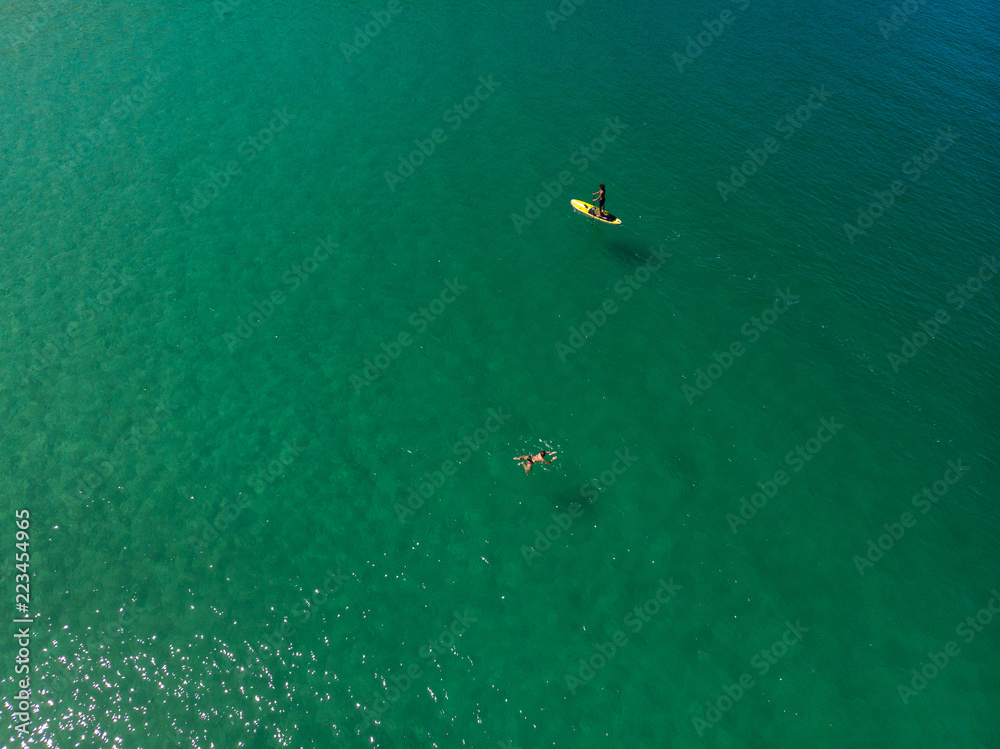  The aerial view of unrecognizable people rises paddle boarding on the surface of the water for sport, and fun. Enjoy the summer SUP activity for holidays.