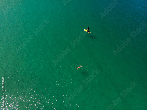  The aerial view of unrecognizable people rises paddle boarding on the surface of the water for sport, and fun. Enjoy the summer SUP activity for holidays.