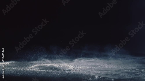 A basketball bouncing in super slow motion on chalk powder leaving white dust behind it giving it a cool effect. The scene has a dark background but the area is spotlit focusing on the ball. photo