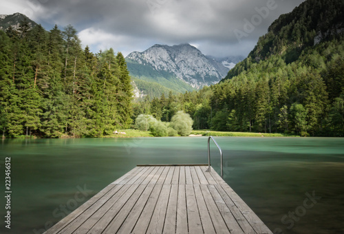 Scenic mountain lake plansarsko view with wooden footbridge in long exposure, slovenia photo