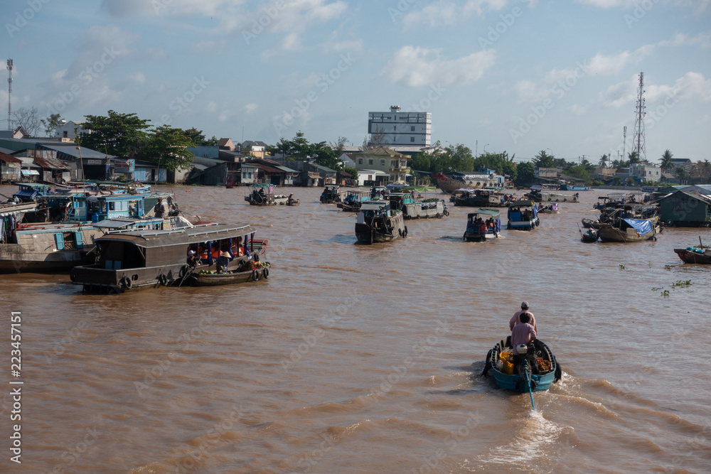 Fototapeta premium Tourists, people buy and sell food, vegetable, fruits on vessel, boat, ship in Cai Rang floating market, Mekong River. Royalty stock image of traffic on the floating market or river market in Vienam