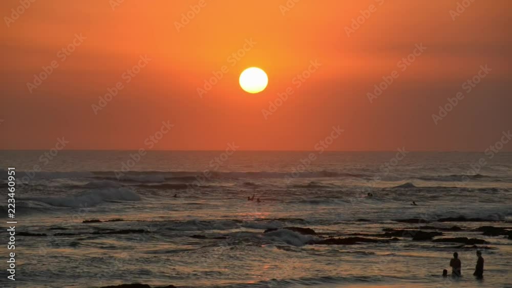 Tropical Sunset Beach with Surfers in Dark Ocean with Big Waves Tropical Sunset Beach with Surfers in Dark Ocean with Big Waves