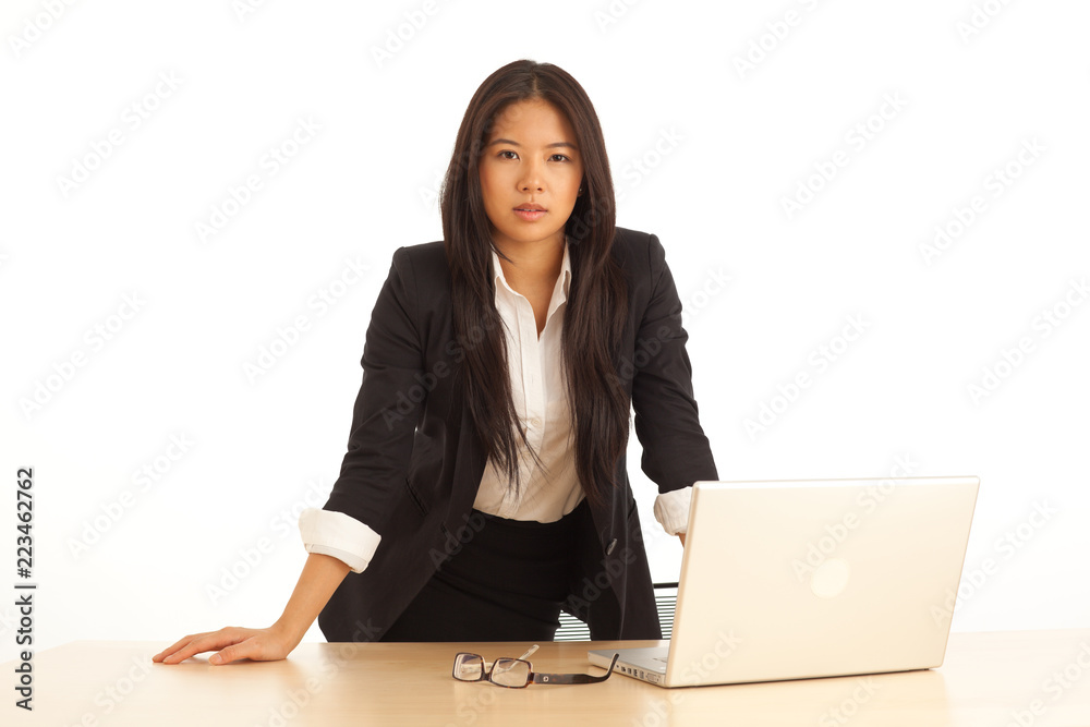 Attractive young business lady standing over desk with laptop computer on white Attractive young business lady standing over desk with laptop computer on white