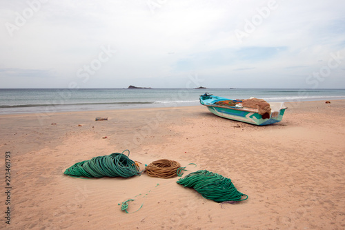 Small coastal fishing boat next to ropes and nets on Nilaveli Beach in Trincomalee state in Sri Lanka Asia