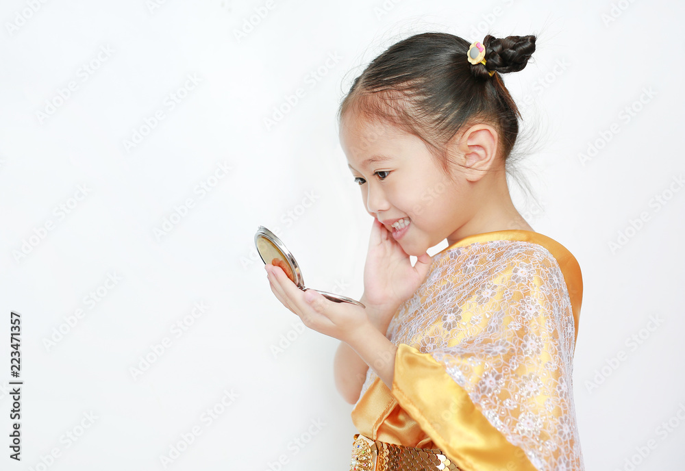 Close-up of Asian child girl in traditional thai dress looking at mirror isolated on white background. Close-up of Asian child girl in traditional thai dress looking at mirror isolated on white background.