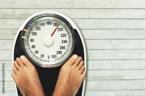 Bare female feet standing on bathroom scale photo