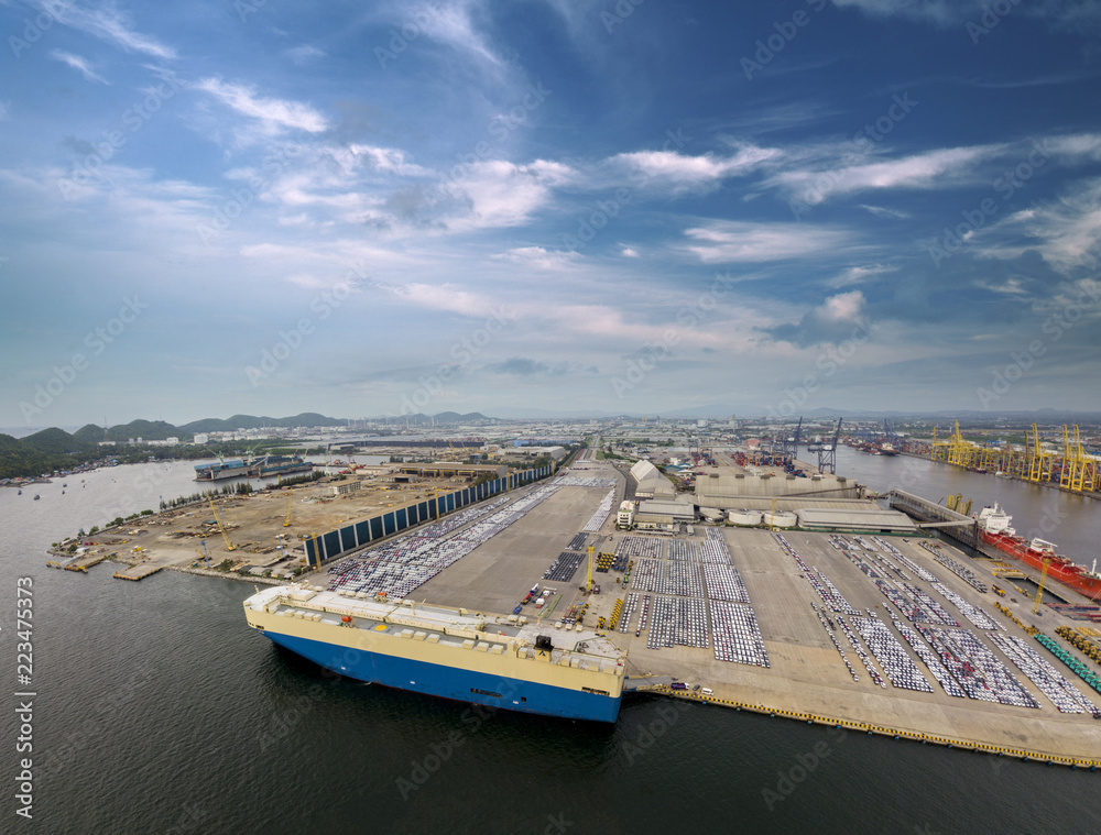 Obraz premium Aerial view of logistics concept commercial vehicles, cars and pickup trucks waiting to be load on to a roll-on/roll-off car carrier ship at Laem Chabang dockyard in Chonburi Province, Thailand
