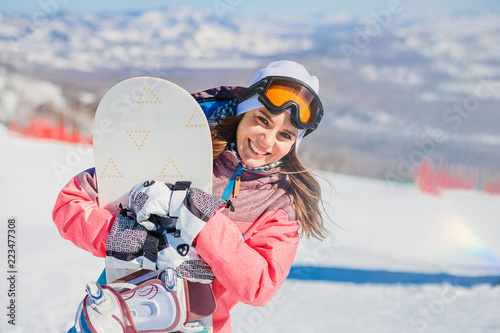 smiling young woman with snowboarding on the mountain in winter