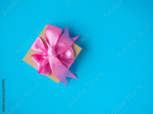 one gift box with pink satin ribbon on a blue background  copy space for text