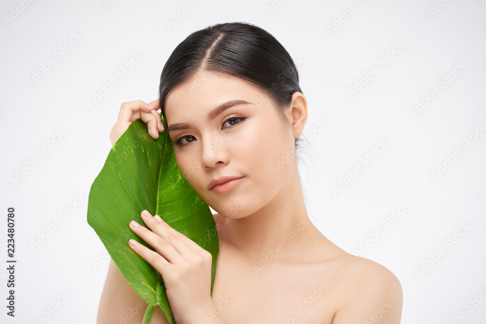 Attractive naked beautiful young woman holding green leaf