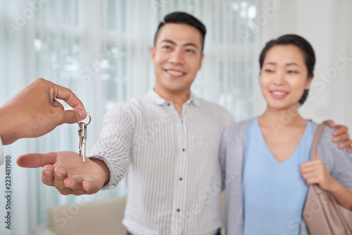 Young Vietnamese couple taking keys after buying new apartment, selective focus