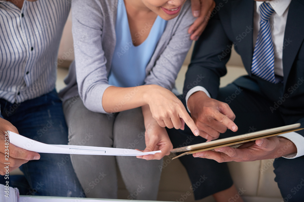 Obraz premium Cropped image of estate agent showing blueprints to couple at meeting