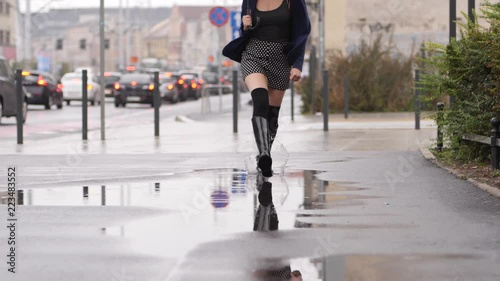 Good mood for rainy weather woman in rubber boots with high bootleg run in puddle with splash