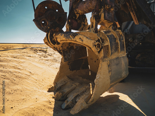 View of sand quarry with havy duty machinery, huge excavator bucket after a working day in the foreground, the impressive size of the time-tested mechanisms at the evening sun, Russia, Chelyabinsk