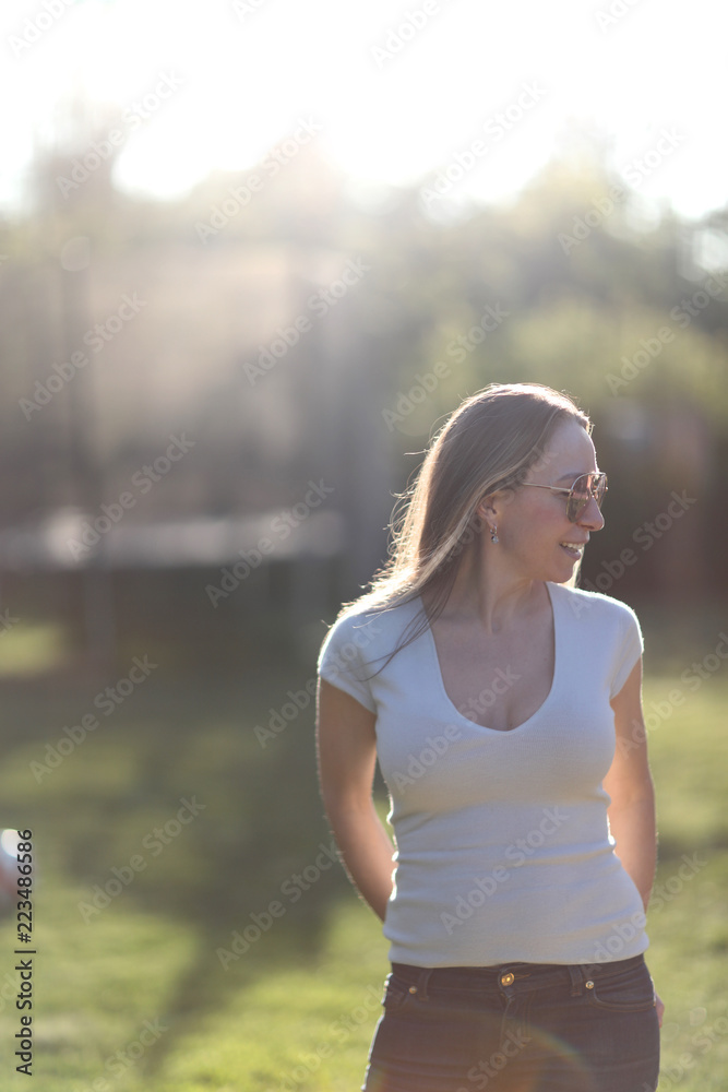 © Anna Jurkovska - Young woman in sunglasses on a green lawn on a sunny day
