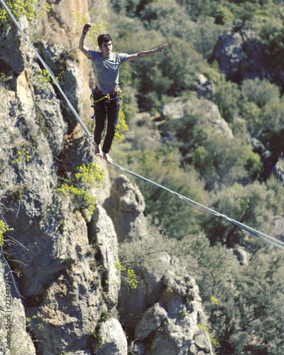 Highliner on a rope. Highline on a background of mountains. Extreme sport on the nature. Balancing on the sling. Equilibrium at altitude.