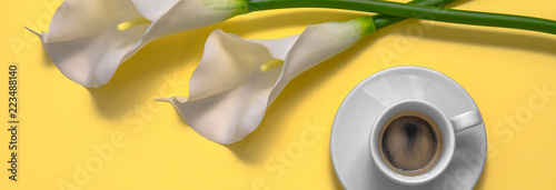 White calla flower with coffee isolated on yellow background. Morning. Flat lay. Top view. Copy space