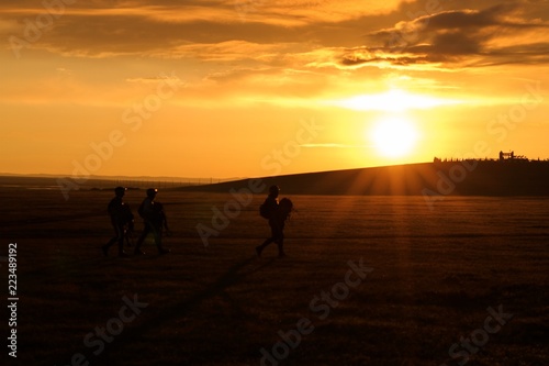 Riders walking out at sunrise below a monument