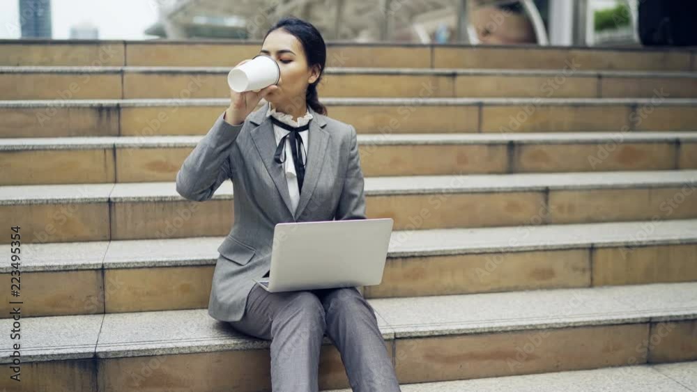 Asian business woman sit on stairs and using her laptop.
Asian business woman sit on stairs and using her laptop.