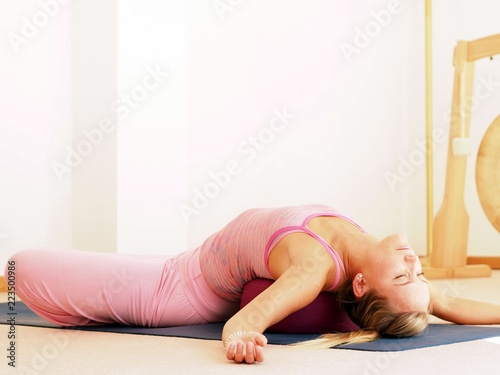 Young attractive woman in a yoga pose wearing a pink sport dress.