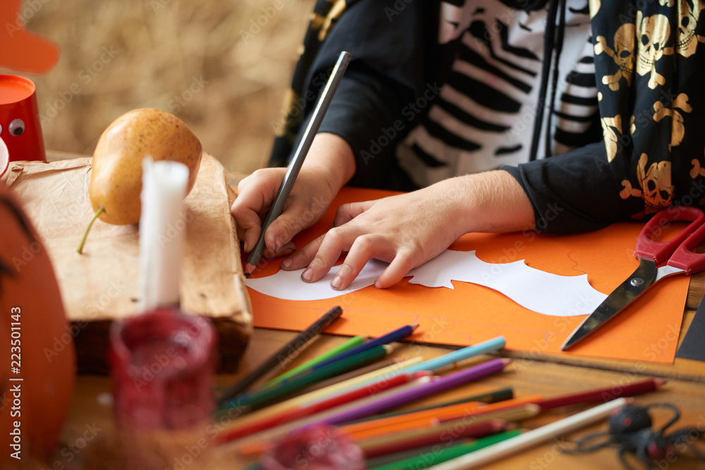 Obraz premium Ręce małego chłopca rysunek nietoperza na kolorowym papierze na Halloween