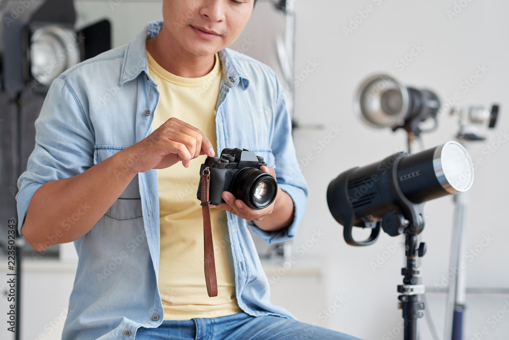 Cropped image of professional photographer checking his camera before shooting in studio