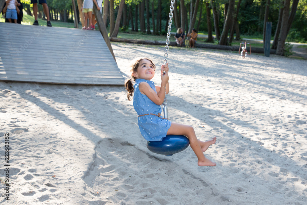 Cute little girl toddler having fun on the playground zip line in city park Cute little girl toddler having fun on the playground zip line in city park